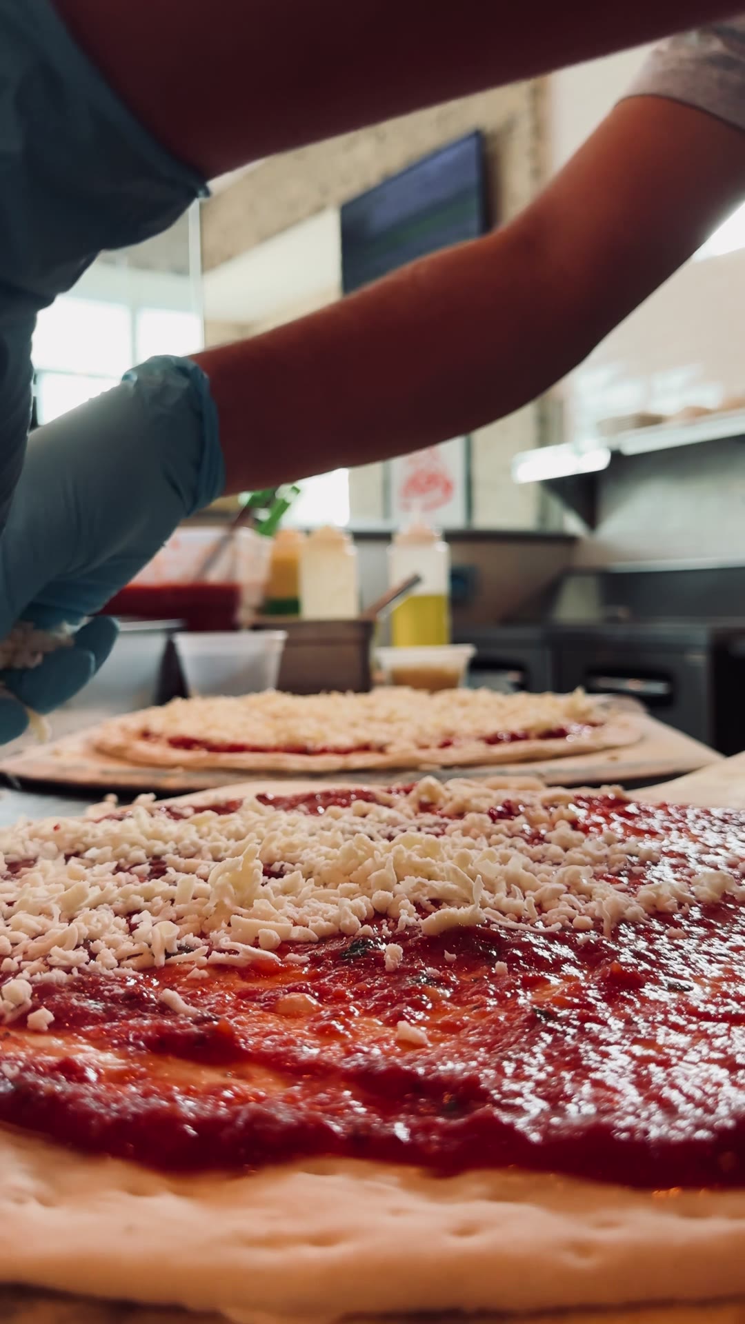 Hand-stretched pizzas being topped at Section Street Pizza