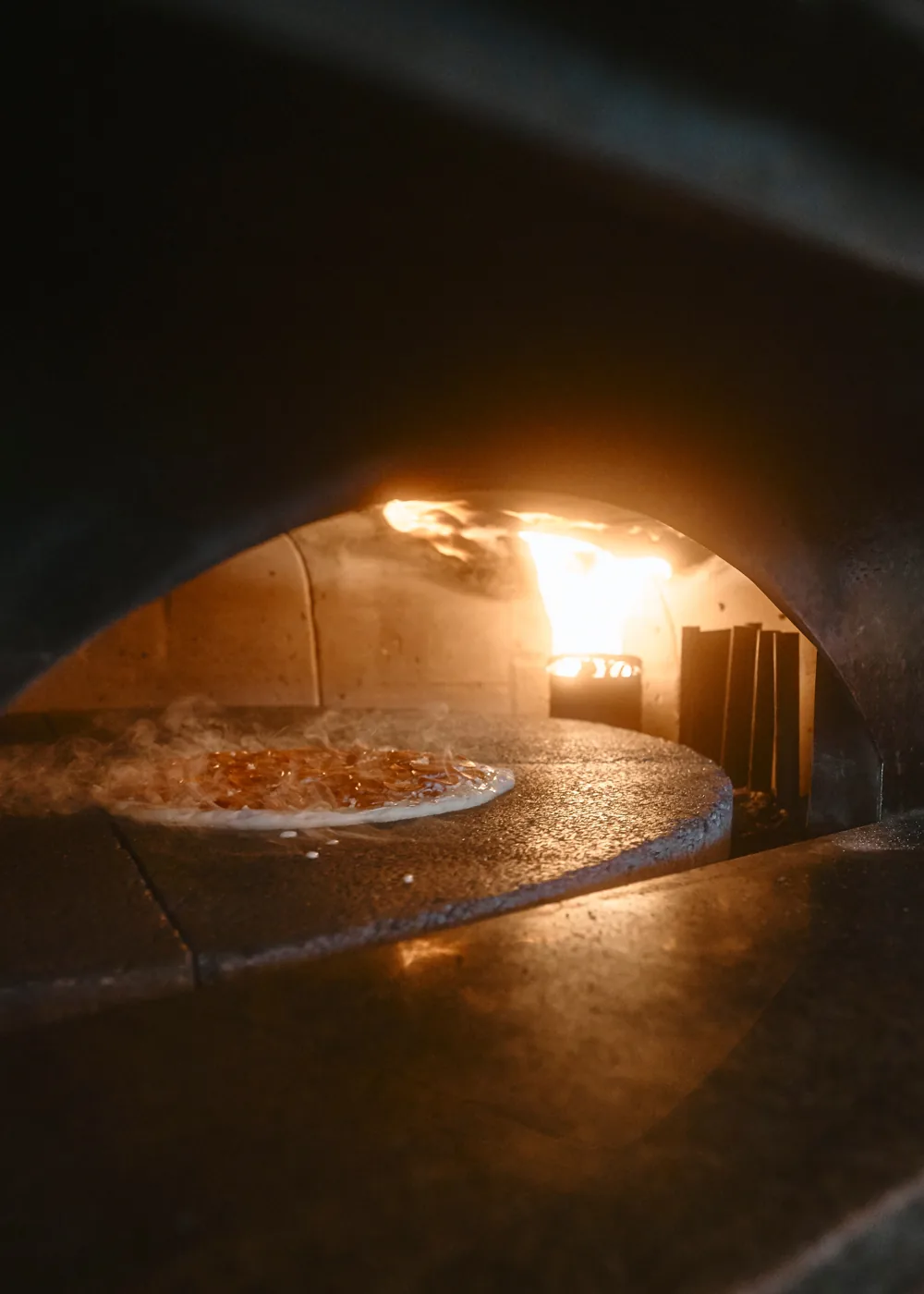 A pie baking in the 700° brick oven beside the open flame